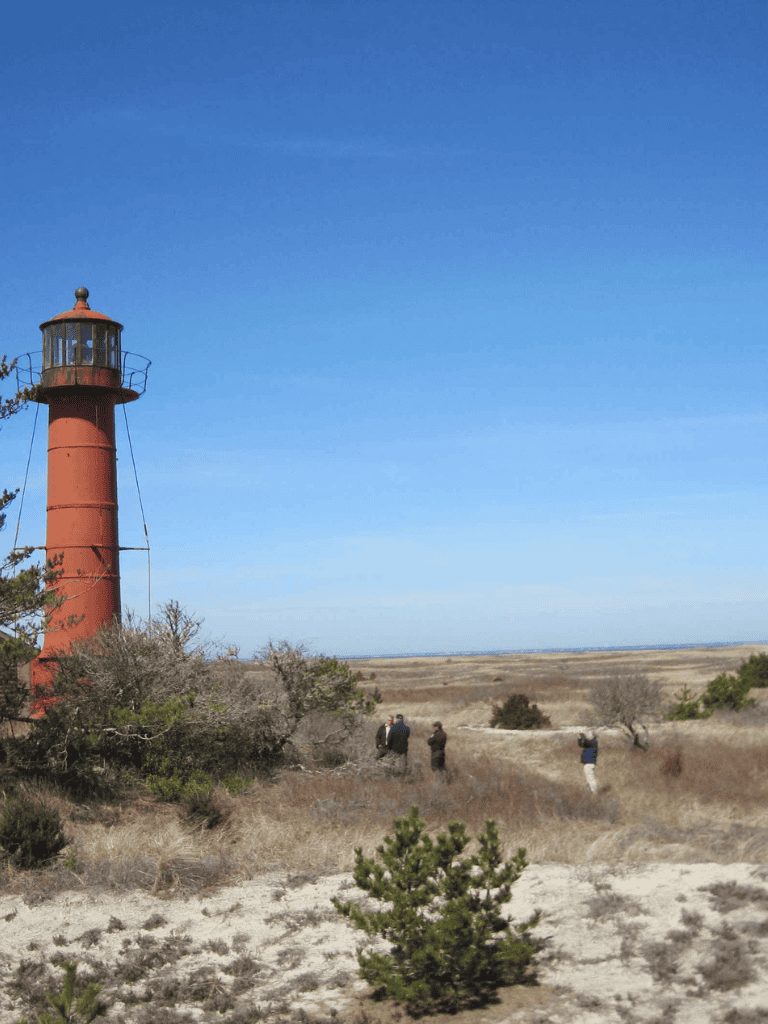Rustic lighthouse on open land with visitors, aiming for navigation and outdoor adventure.