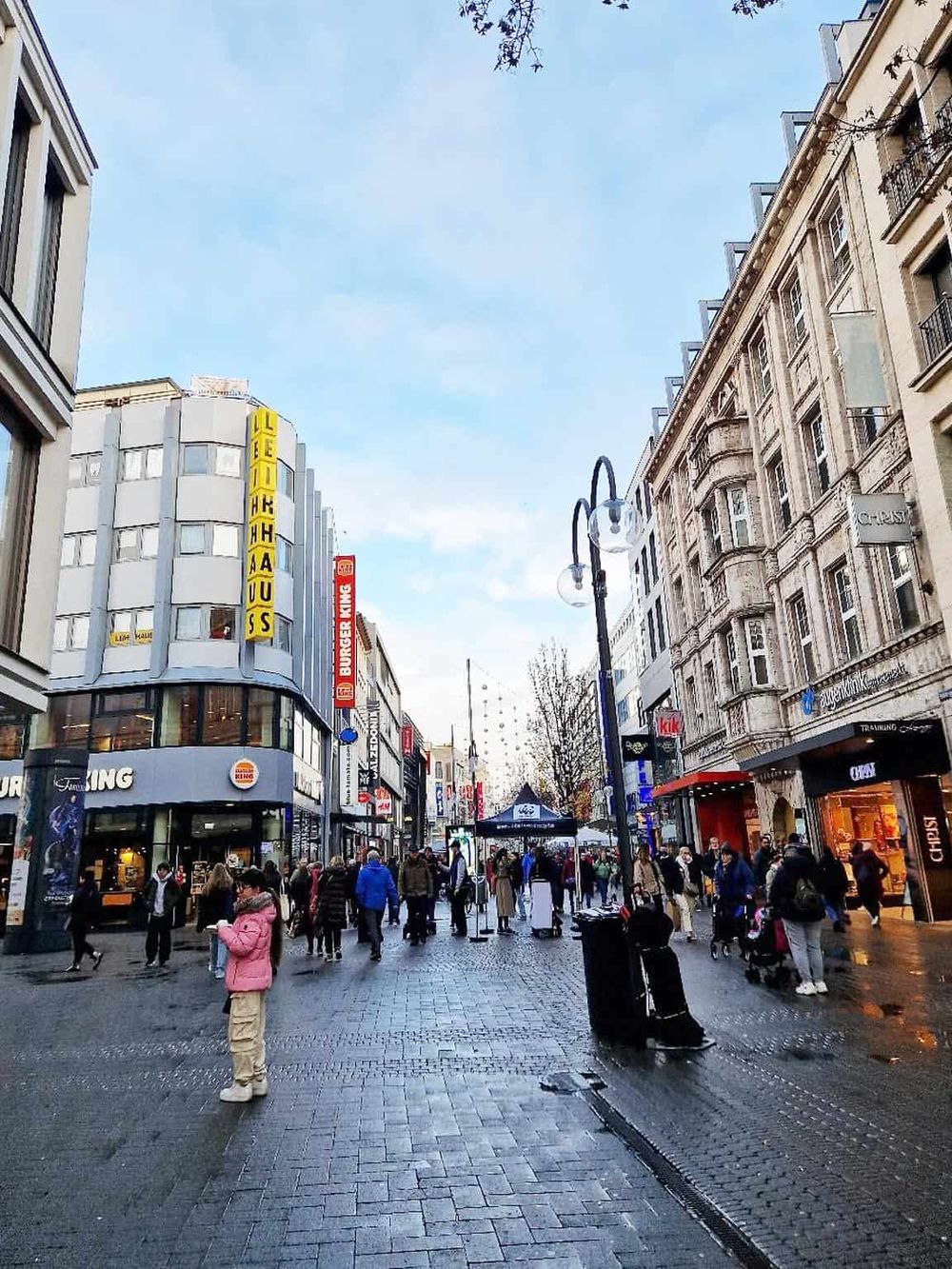 Bustling city street with shops, pedestrians, and streetlights, highlighting urban navigation and downtown shopping.
