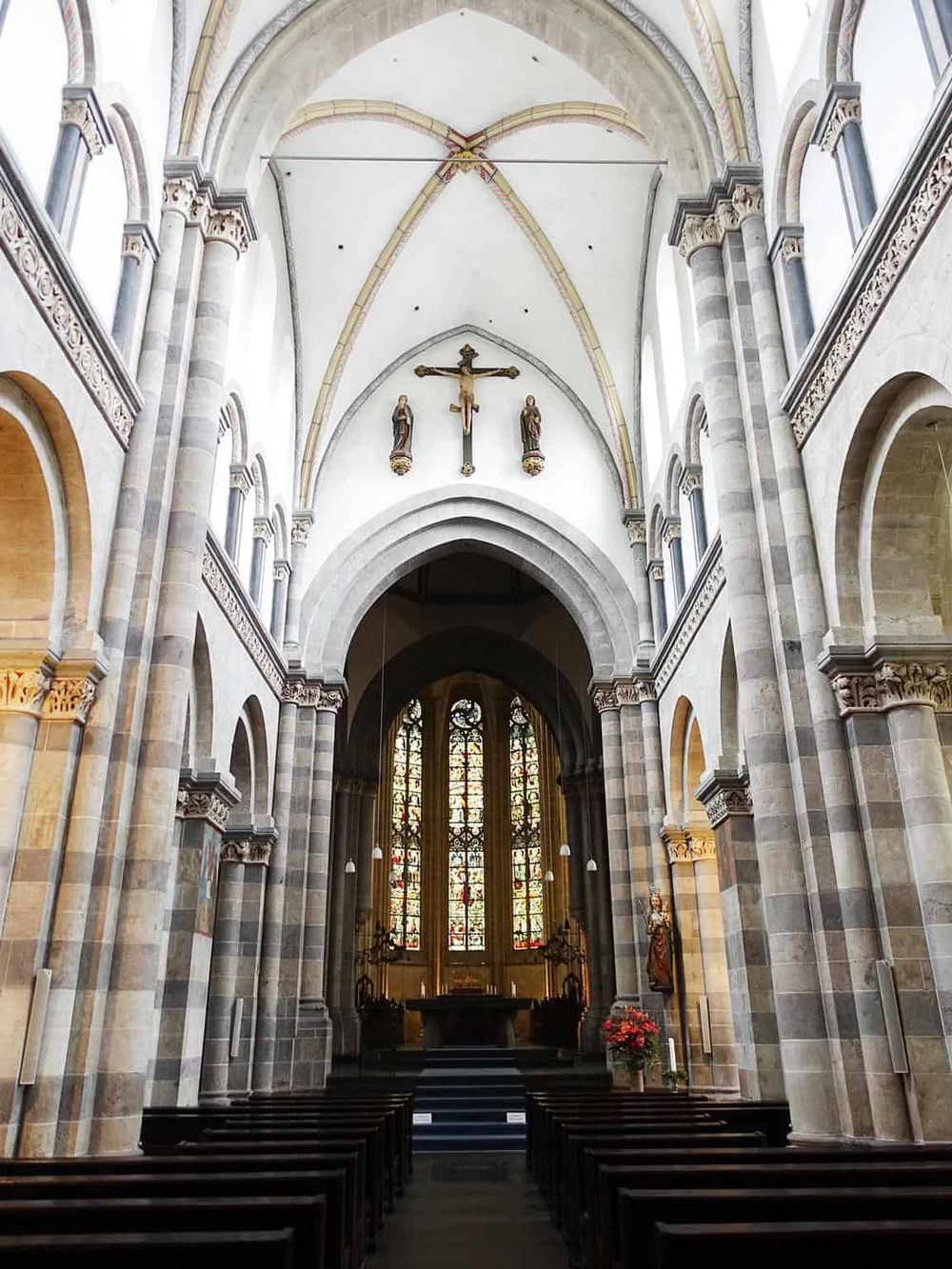 Serene interior of a historic church with stained glass windows and religious sculptures.