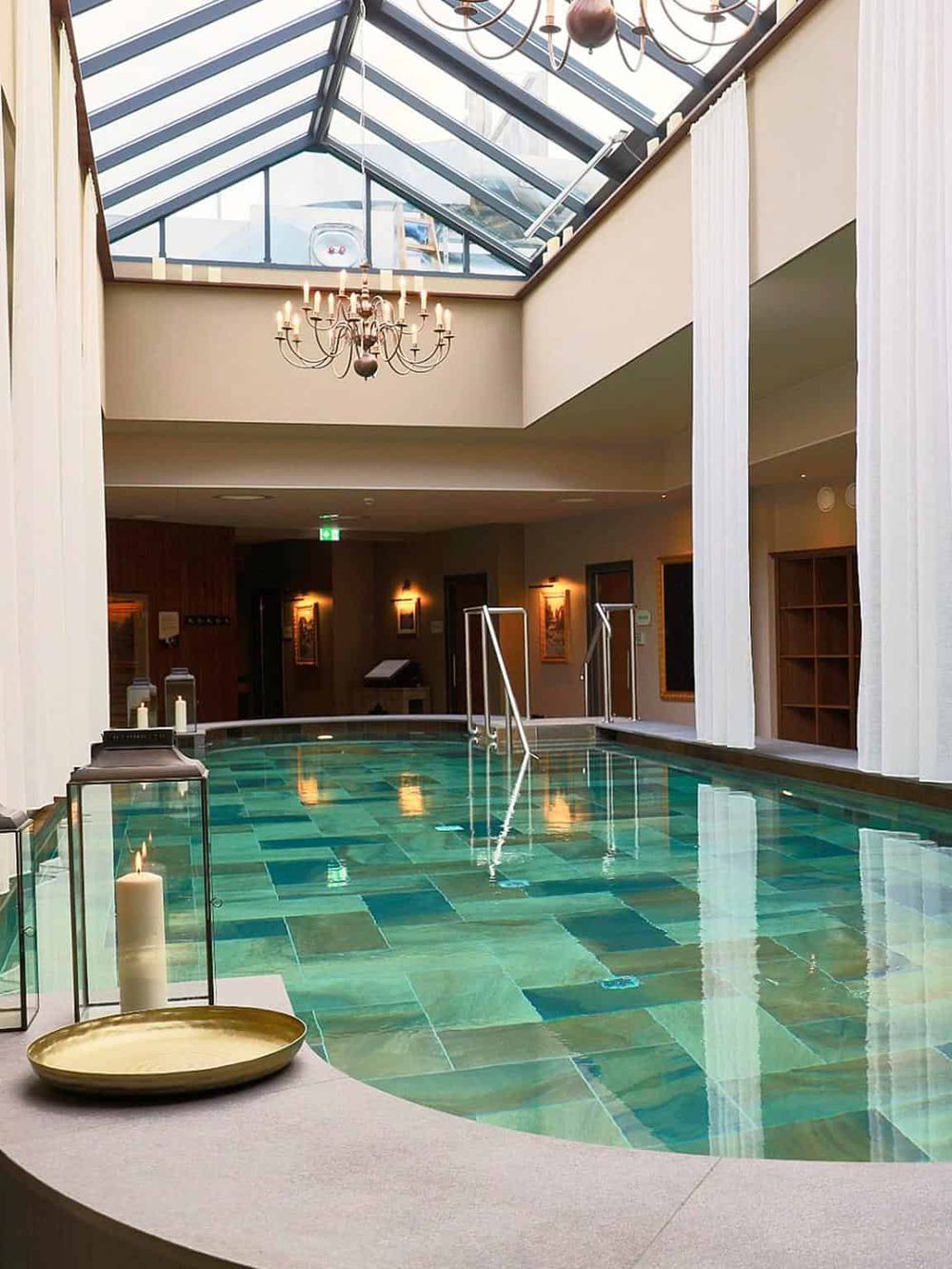 Luxurious indoor swimming pool with glass skylight, elegant chandelier, and serene ambiance for relaxation.