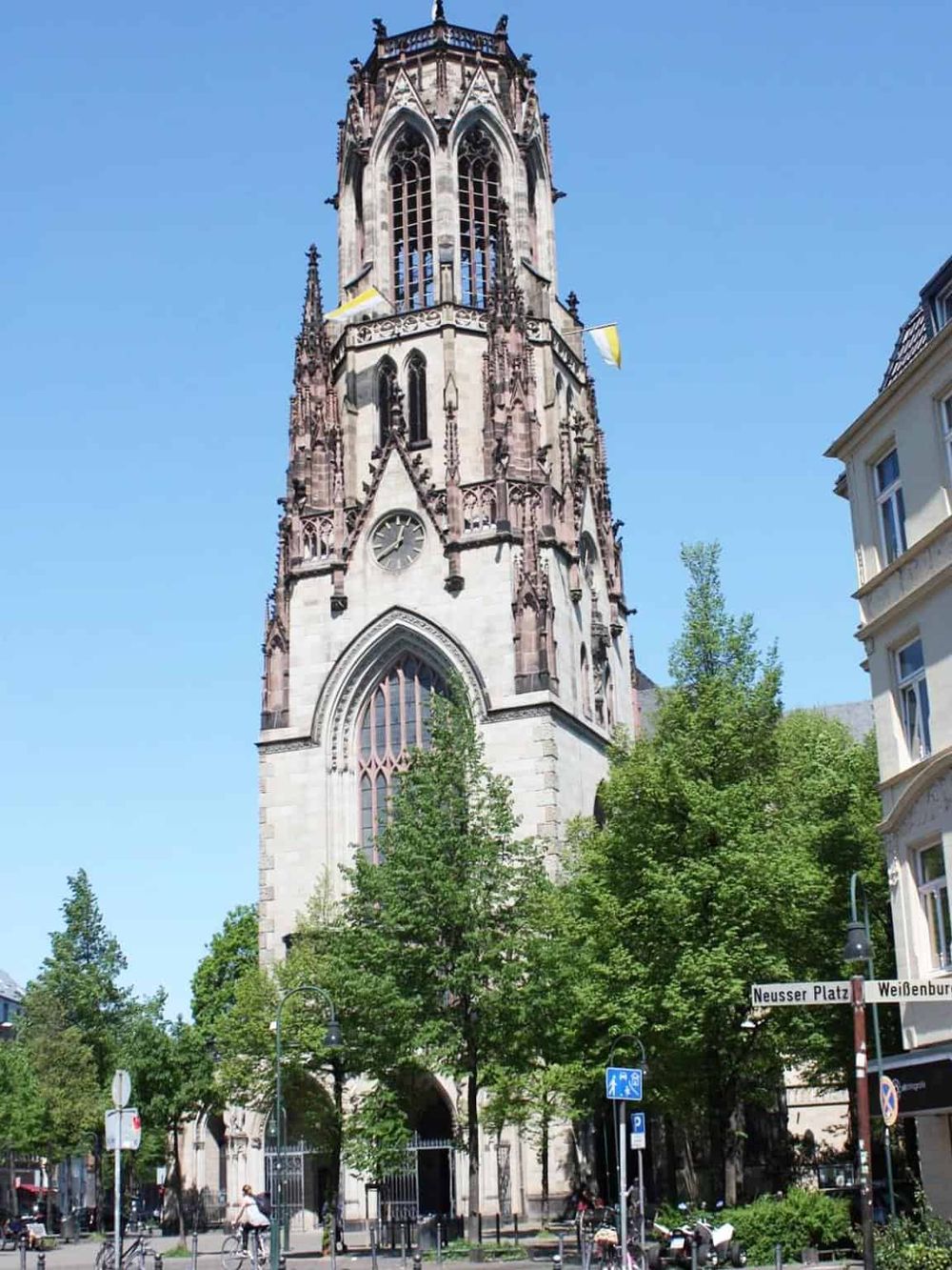 Historic Gothic church tower in Heidelberg, Germany, near Neusser Platz. Iconic architectural landmark under clear blue sky.