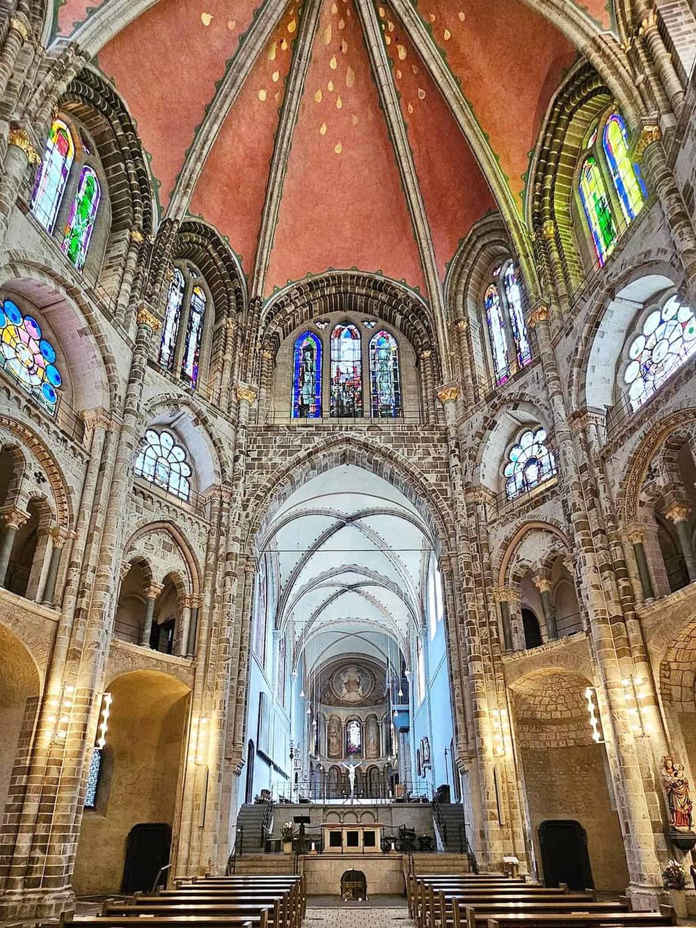 Stunning Gothic cathedral interior with stained glass windows and intricate architecture.