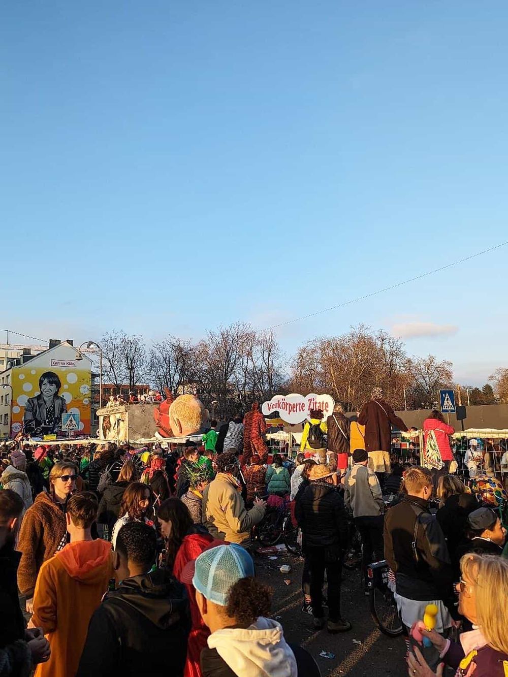 Busy outdoor market with diverse crowd shopping and enjoying the day, vibrant atmosphere, clear skies.