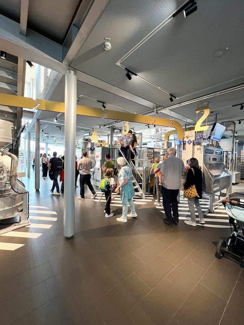 Crowd at airport security checkpoint with numbered signs, modern design, and diverse travelers waiting.