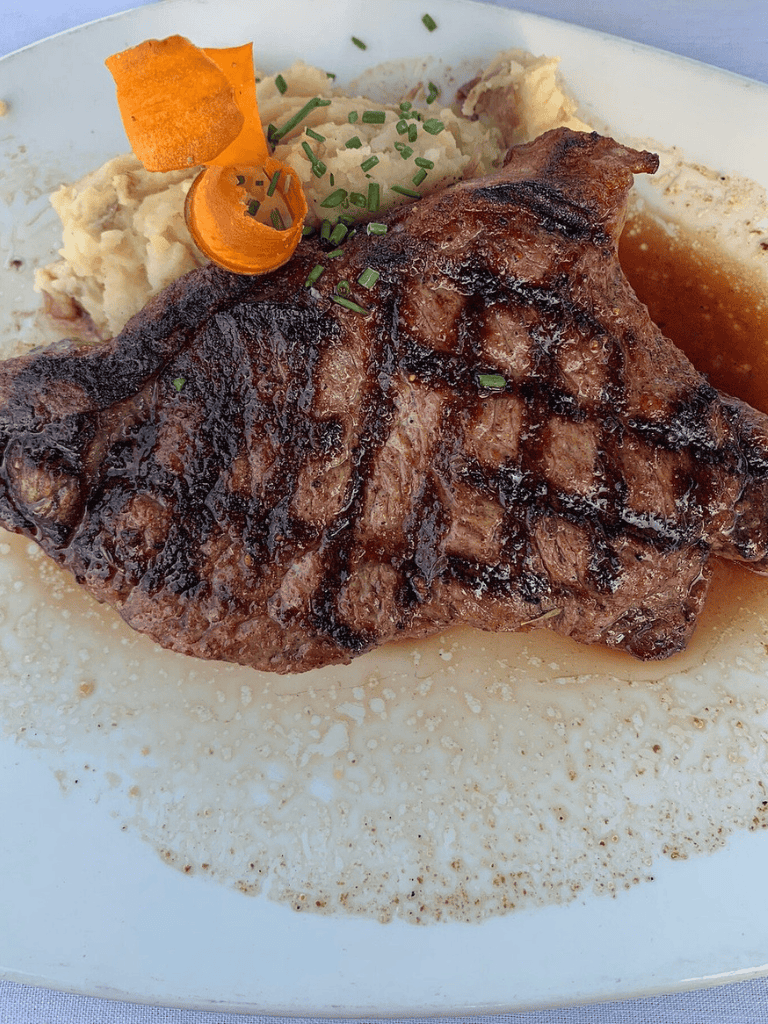 Juicy grilled steak with mashed potatoes and fresh herbs, served with savory gravy. Perfect for a satisfying meal.