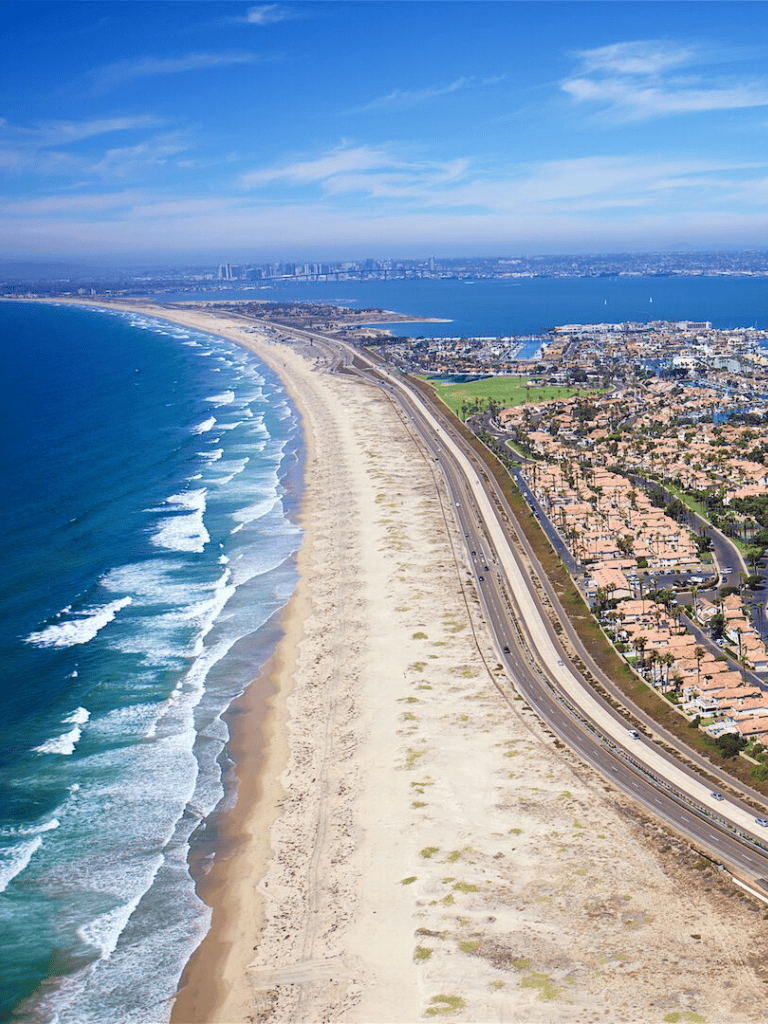 Aerial view of coastal highway and ocean beach near QuestForDirections, California shoreline.