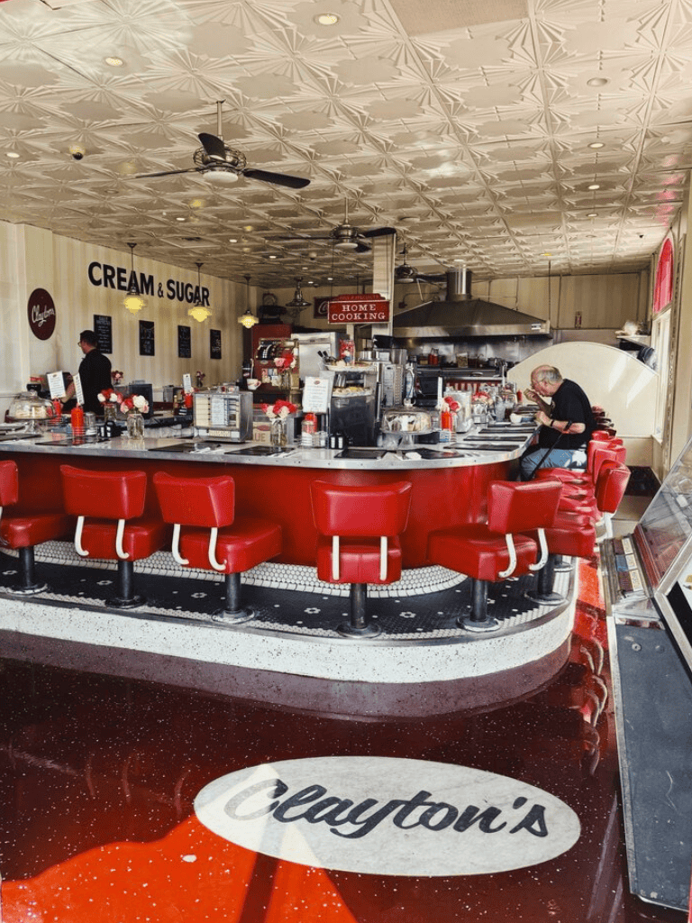 Cream and Sugar donut shop interior with red seating and bakery equipment, inviting place for sweet treats and breakfast.