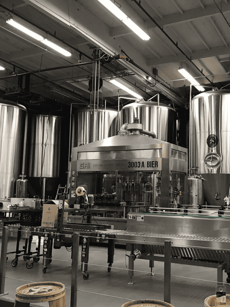 Stainless steel beer brewing equipment in a brewery production area.