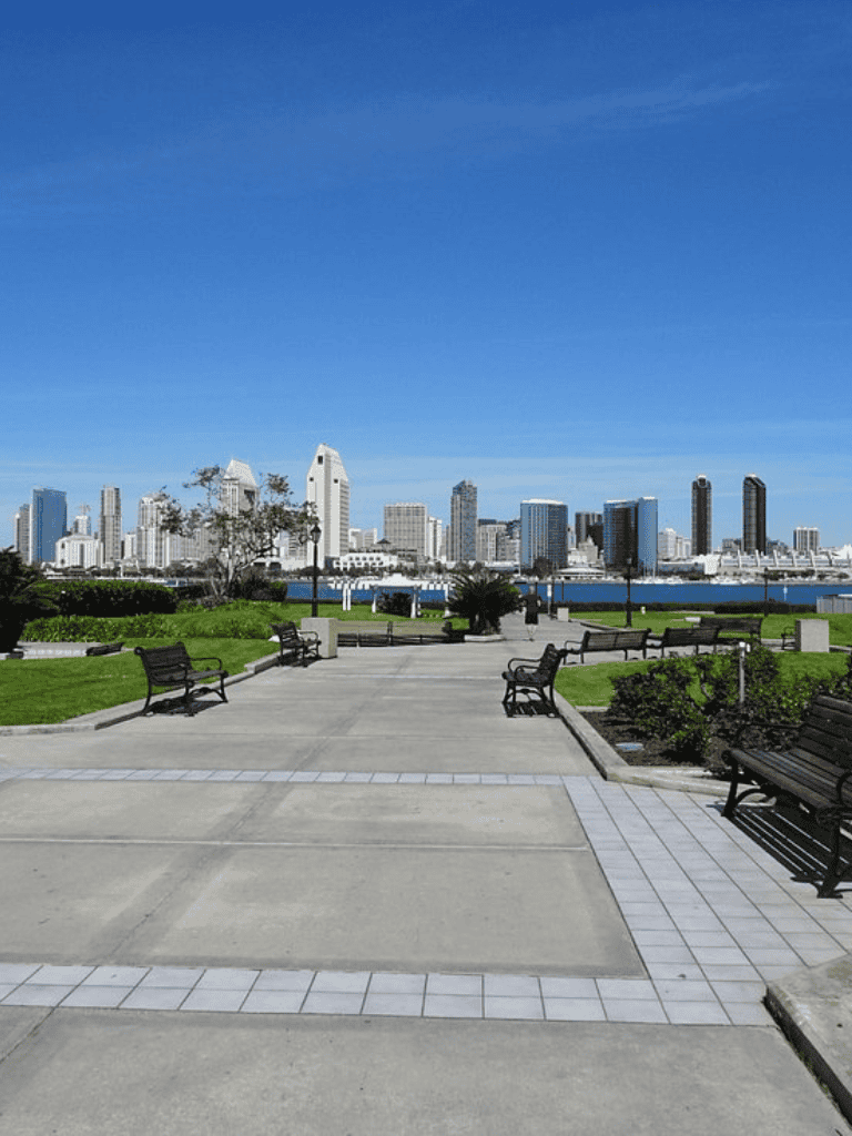 Modern cityscape with skyline view from park, outdoor benches, and walking paths for urban exploration.