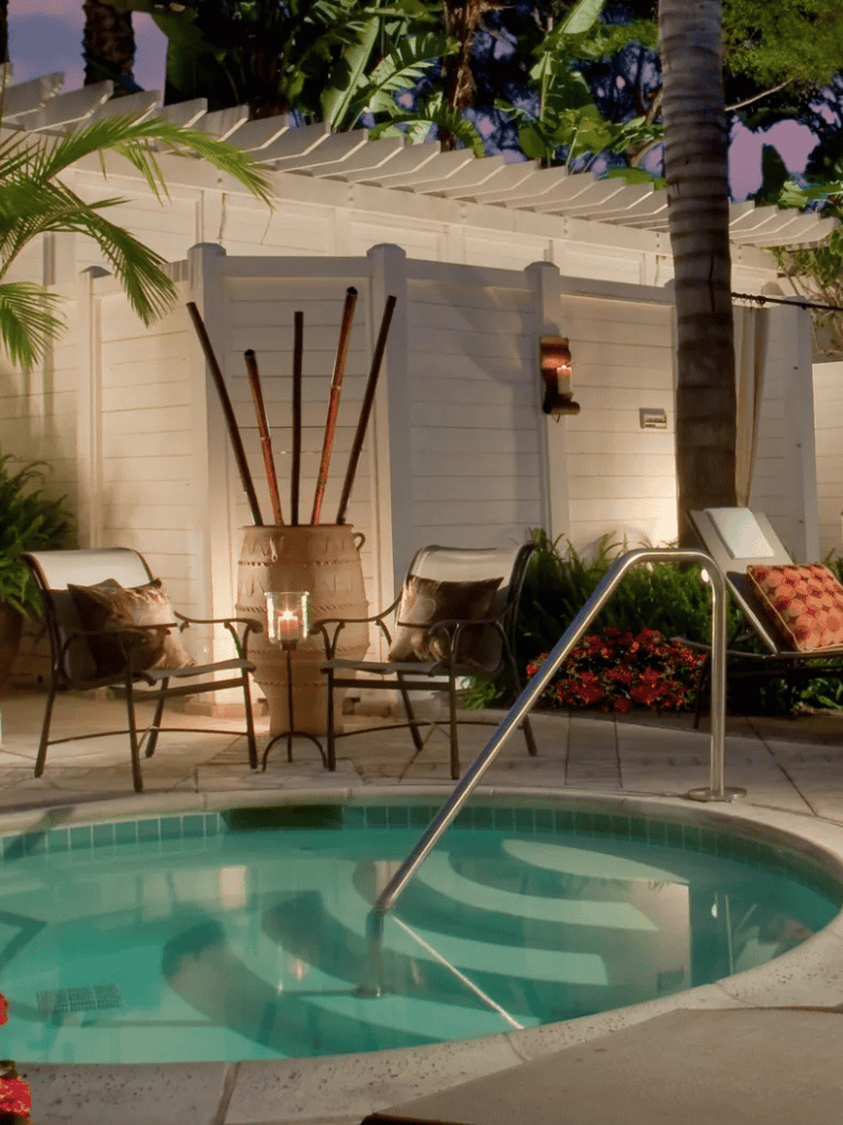 Relaxing poolside outdoor seating area with tropical plants and ambient lighting.