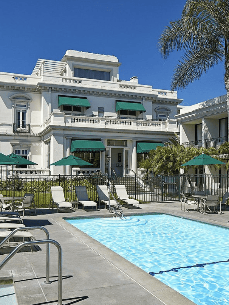 Luxury hotel with pool and lush greenery in a sunny, tropical setting.