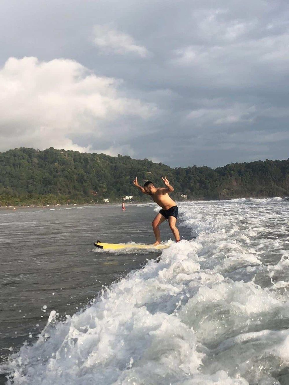 1. Man surfing on the ocean waves on a cloudy day, enjoying beach adventure activities.