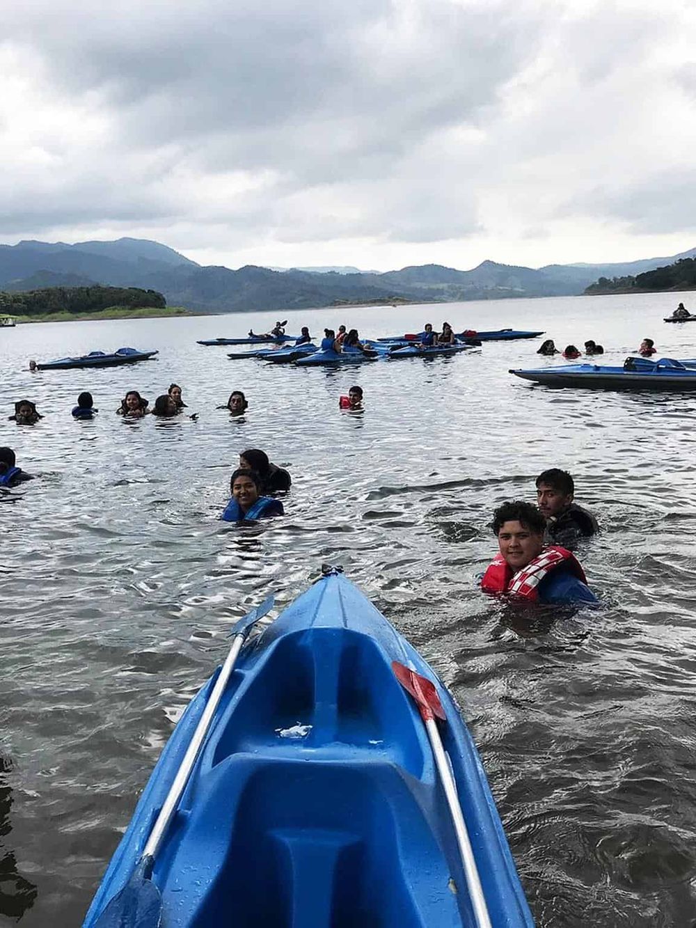 Kids enjoying kayaking adventure on scenic lake with mountains in the background.