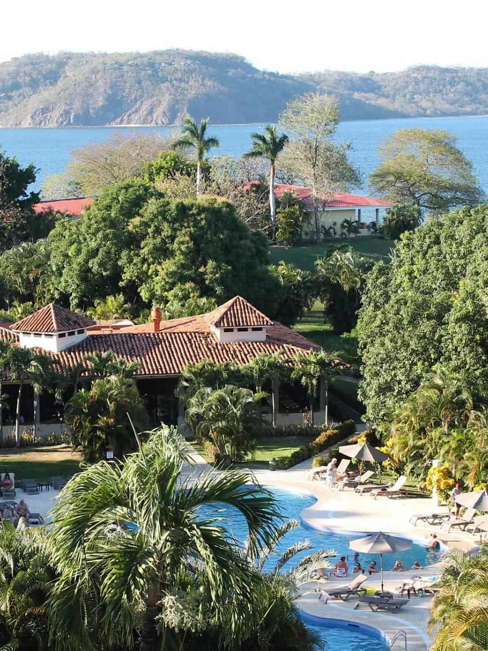 Luxurious tropical resort with swimming pool, lush gardens, and scenic water views.