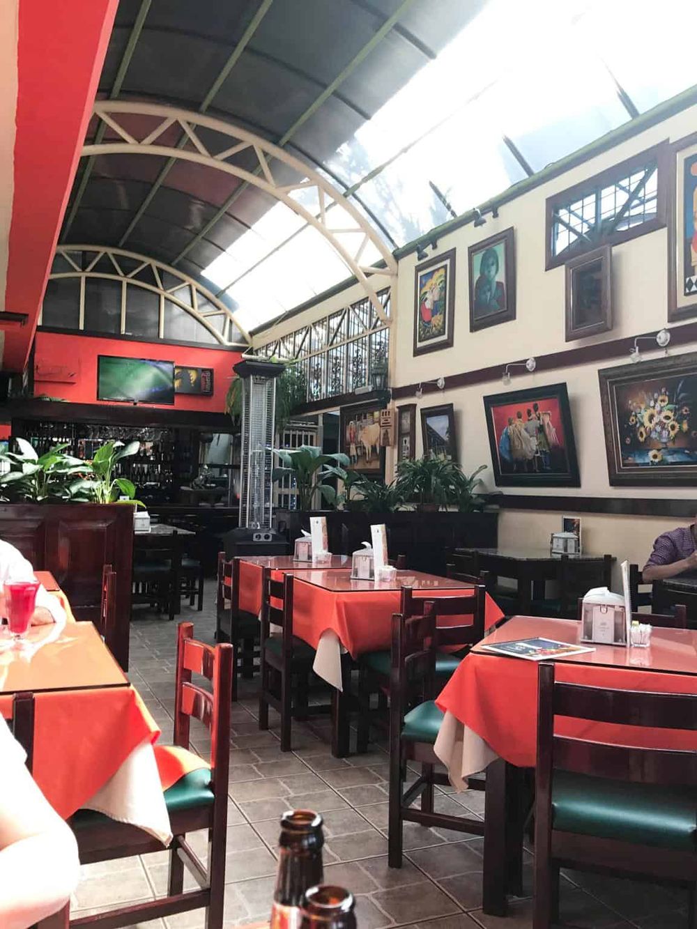 Bright indoor dining area with vibrant red tablecloths and artwork, featuring a spacious, modern, and inviting atmosphere.
