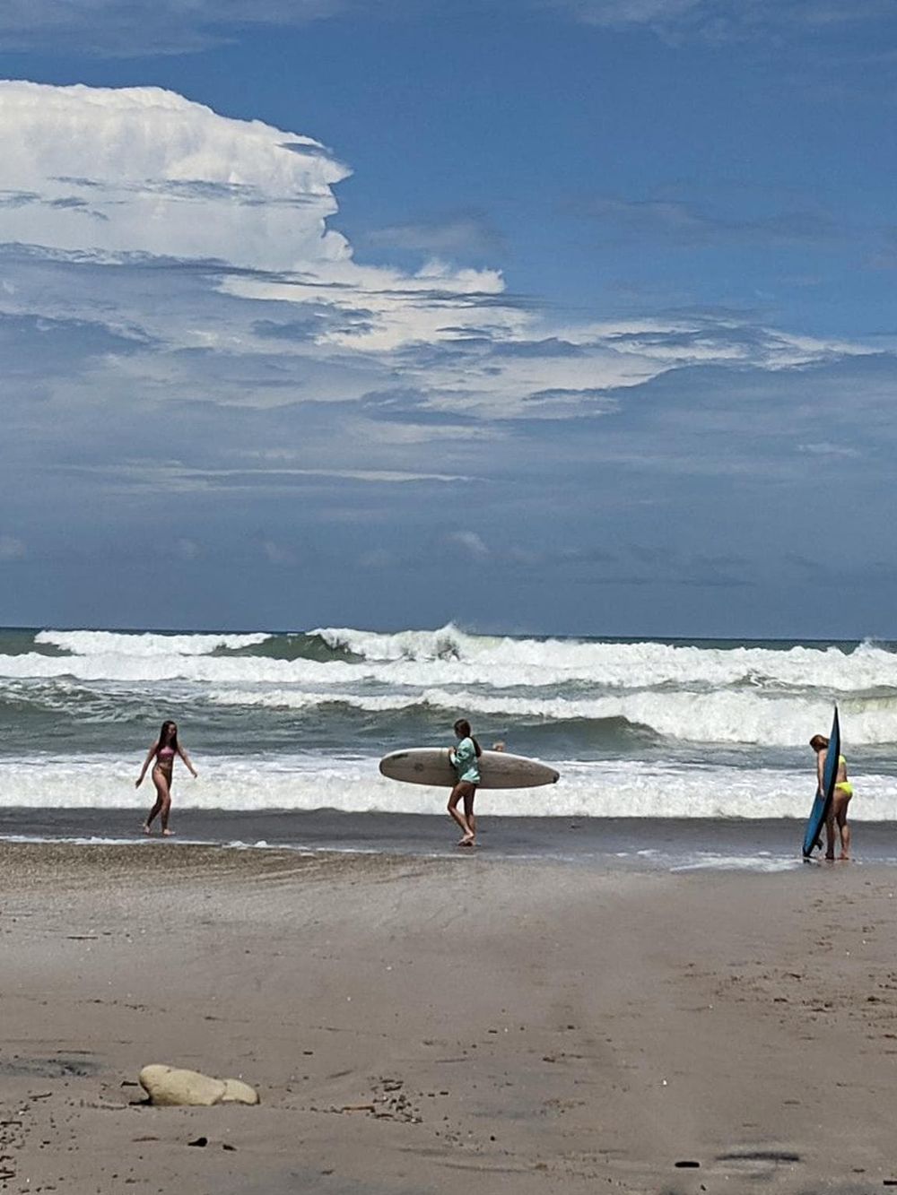 Surfers and beachgoers enjoying the ocean waves at a scenic coastal location.