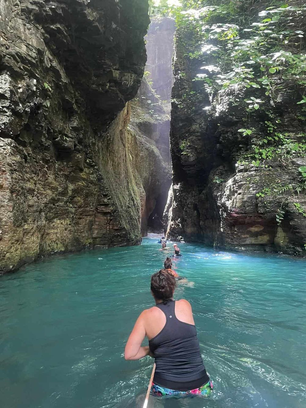 Serene canyon waterway with adventurers exploring scenic turquoise river and lush cliffs.