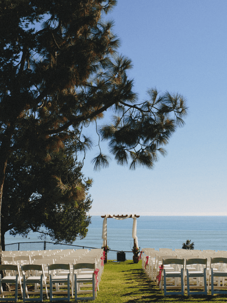 Elegant beachfront wedding setup over overlooking ocean with chairs, flowers and arch, perfect for scenic wedding ceremonies.
