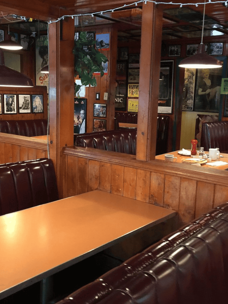 Cozy restaurant booth with wooden interior and vintage wall decor, perfect for casual dining.
