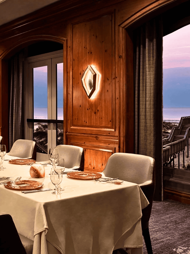 Cozy dining room with ocean view, elegant table setup, and warm wooden decor for memorable dining experiences.