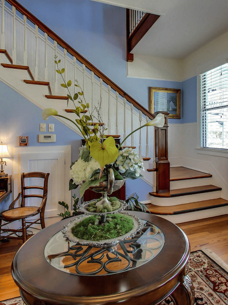 Elegant home interior with staircase, floral centerpiece, and classic decor – QuestForDirections.