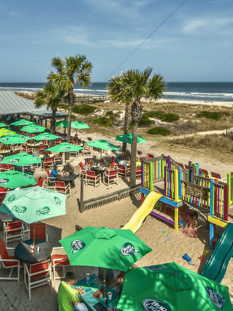 Relaxing beachside restaurant with outdoor seating, colorful playground, and ocean views.