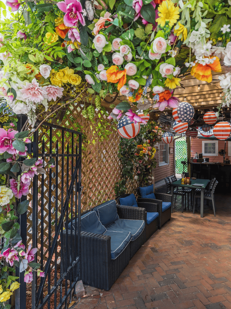 Colorful floral outdoor cafe with cozy seating and patriotic decorations for summertime events.