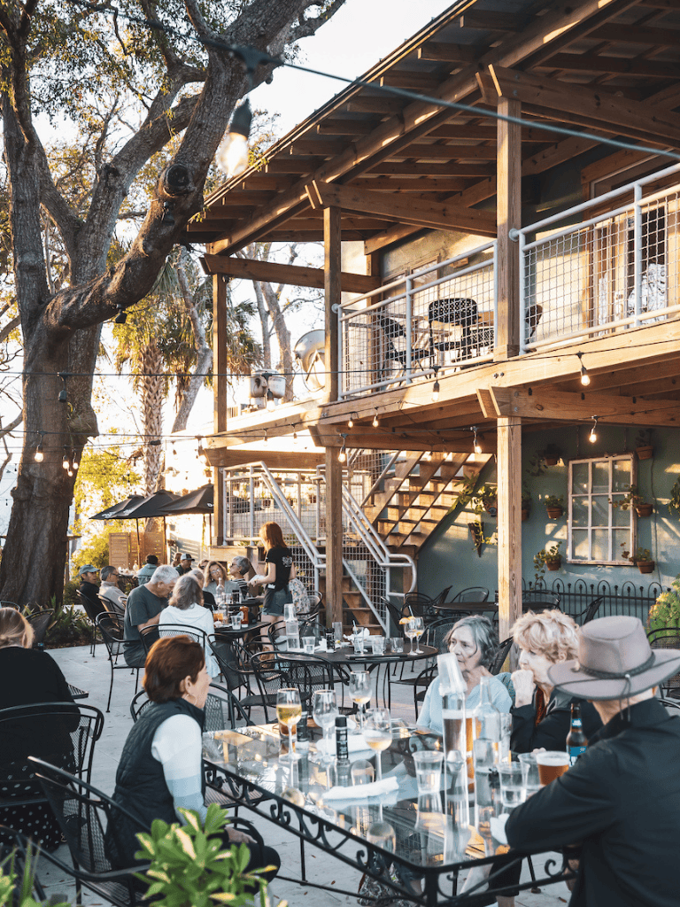 Aluminum outdoor dining furniture with glass tables in a lively patio setting.