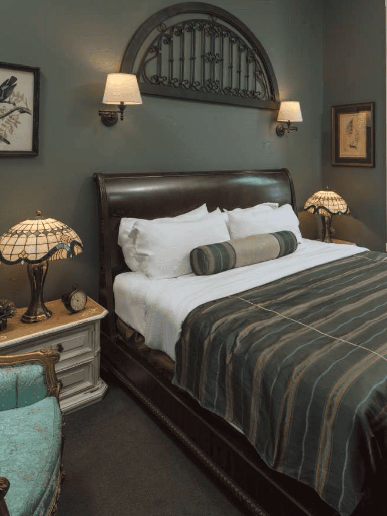 Cozy bedroom with vintage decor, leather bed, bedside lamps, and classic artwork for a relaxing stay.