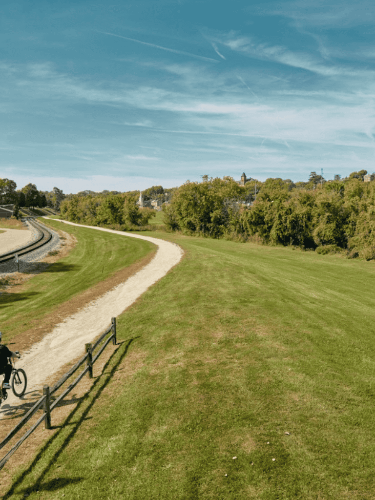 Scenic walking trail with lush green grass and clear blue sky, ideal for outdoor activities and exploration.