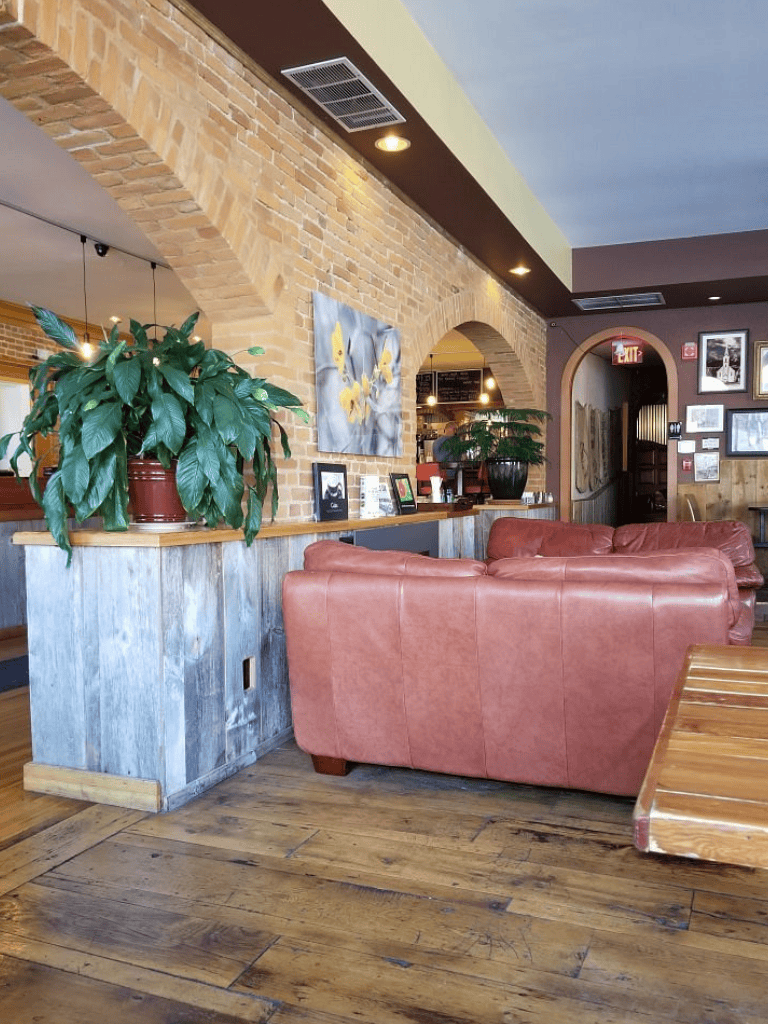 Cozy café interior with brick walls, green plants, and comfortable seating, perfect for relaxing or working.