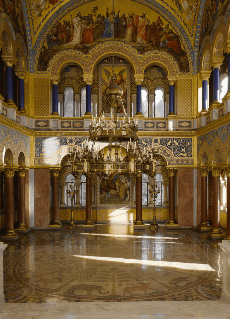 Opulent church interior with gold accents, chandelier, frescoes, and intricate architectural details.
