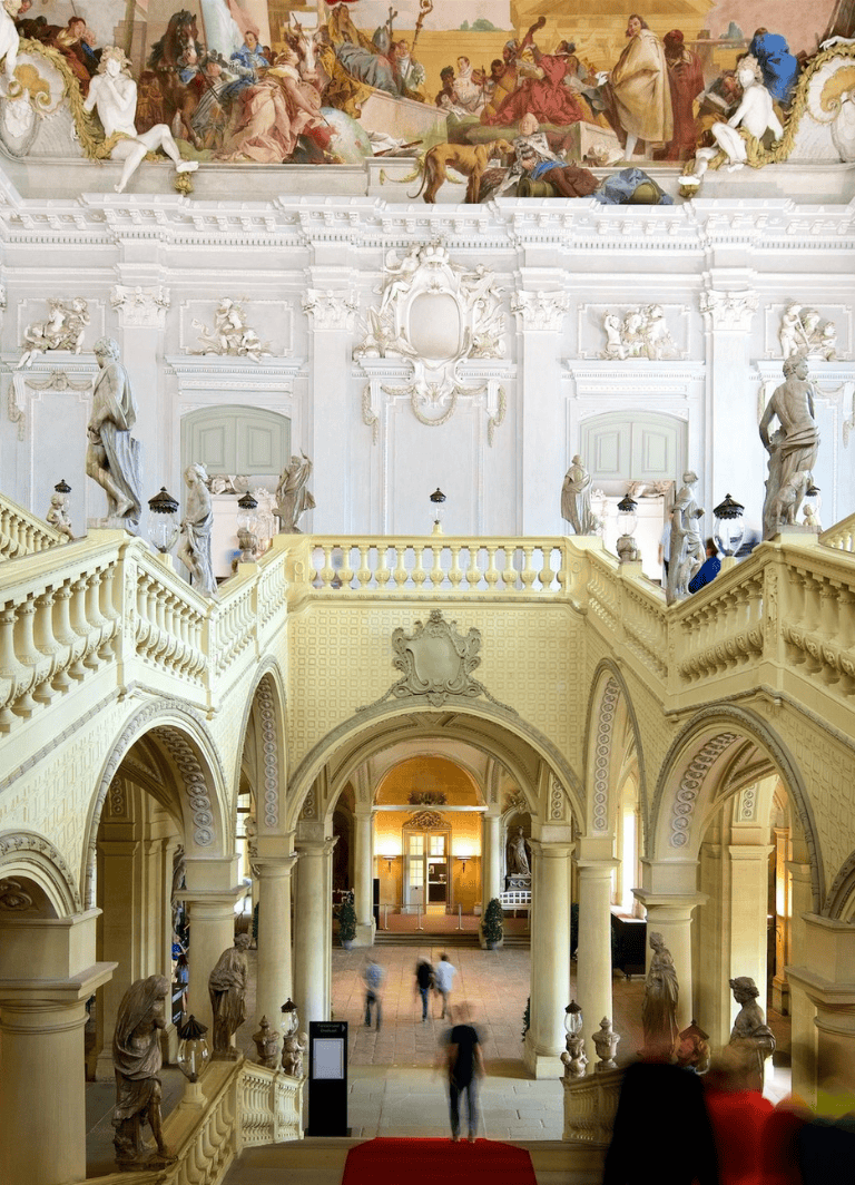 Ornate historic palace interior with classical statues and intricate architectural details.