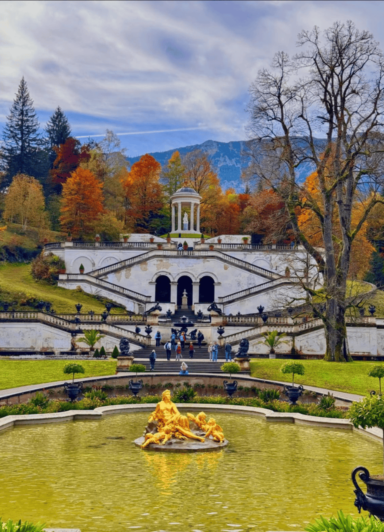 Elegant historic palace with lush gardens and mountainous backdrop, perfect for sightseeing and outdoor exploration.