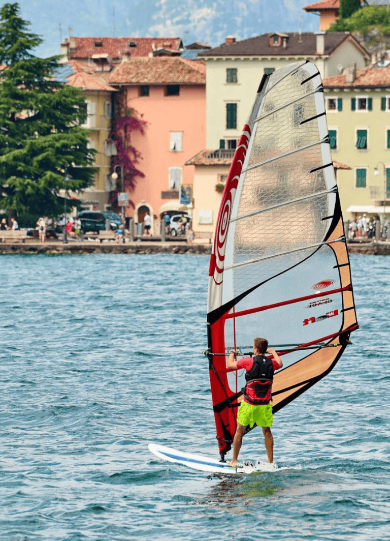 Speed sailing on lake with colorful European town in background.