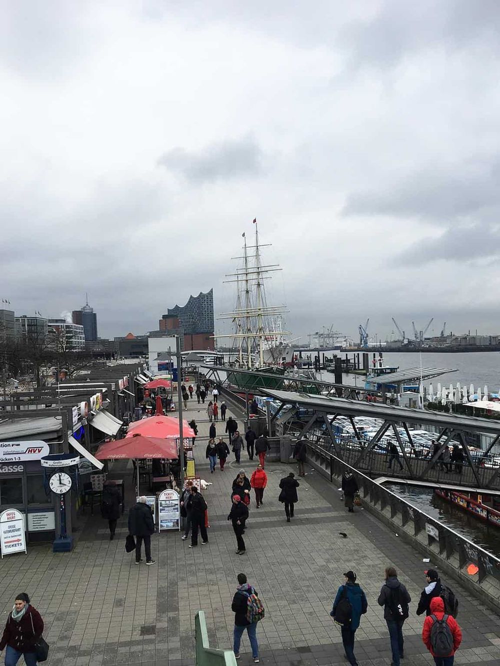 Historic Hamburg harbor with ships, pedestrians, and modern city skyline, Germany.