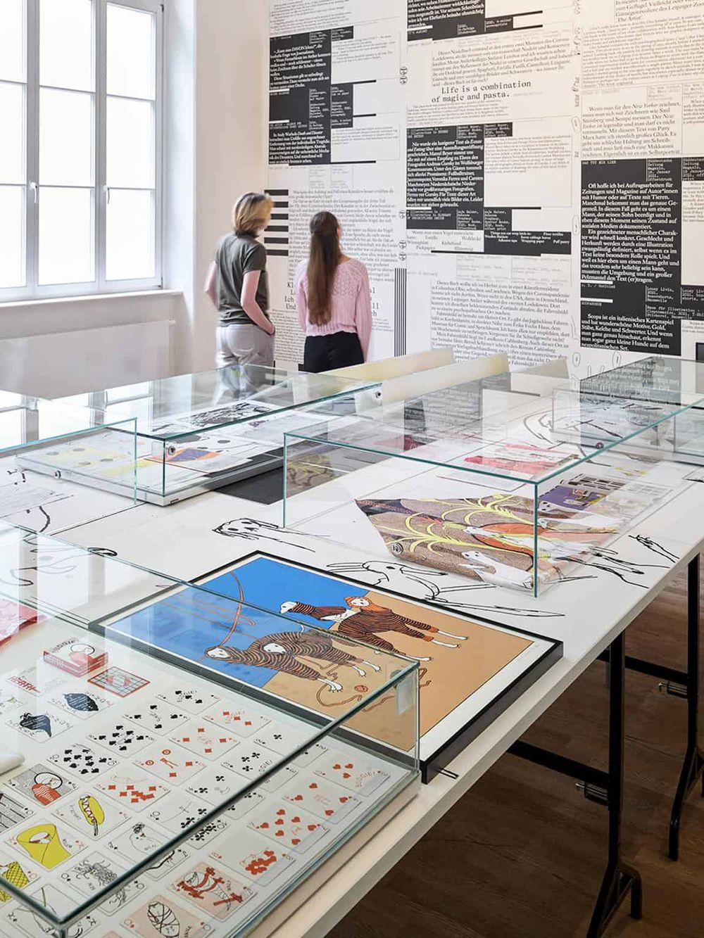 Colorful art and design exhibition with glass display cases and visitors exploring contemporary artwork.