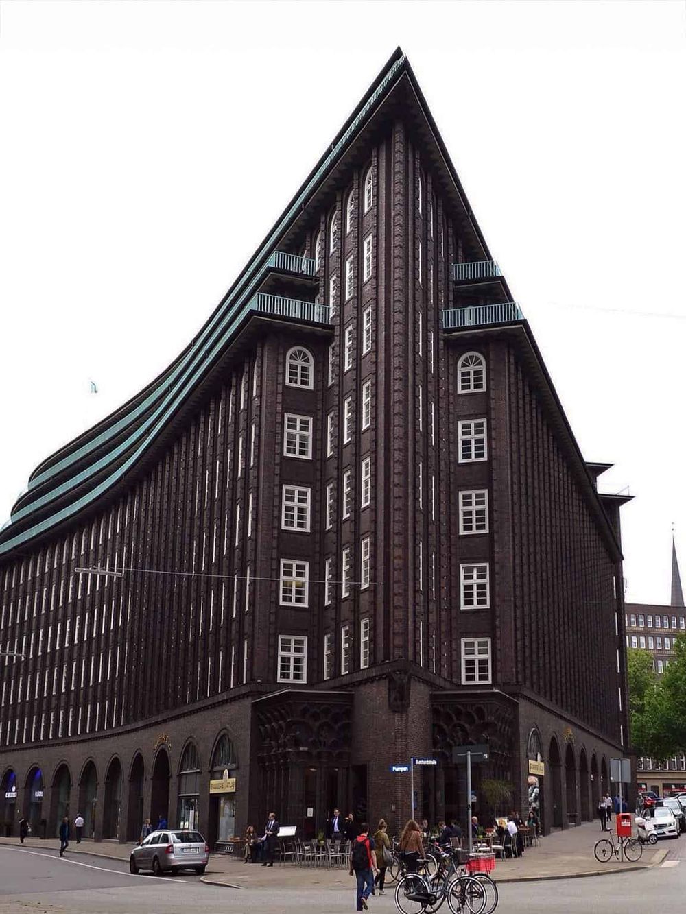 Modern historic building in Berlin with curved architecture, office spaces, pedestrians, and cyclists on the street.