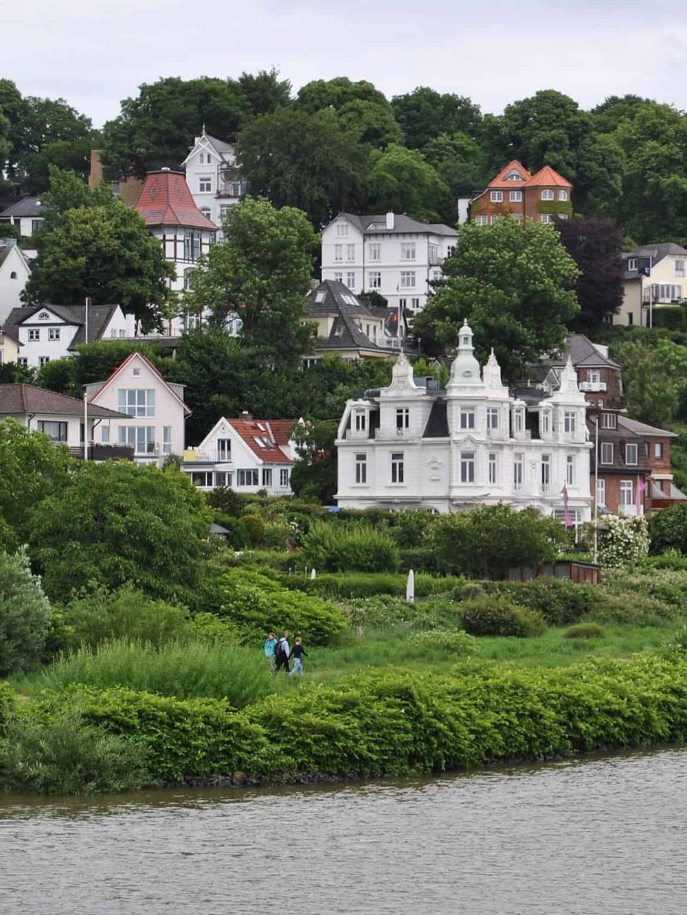 Colorful hillside homes in Newport, Rhode Island with lush greenery and a historic mansion by the waterfront.