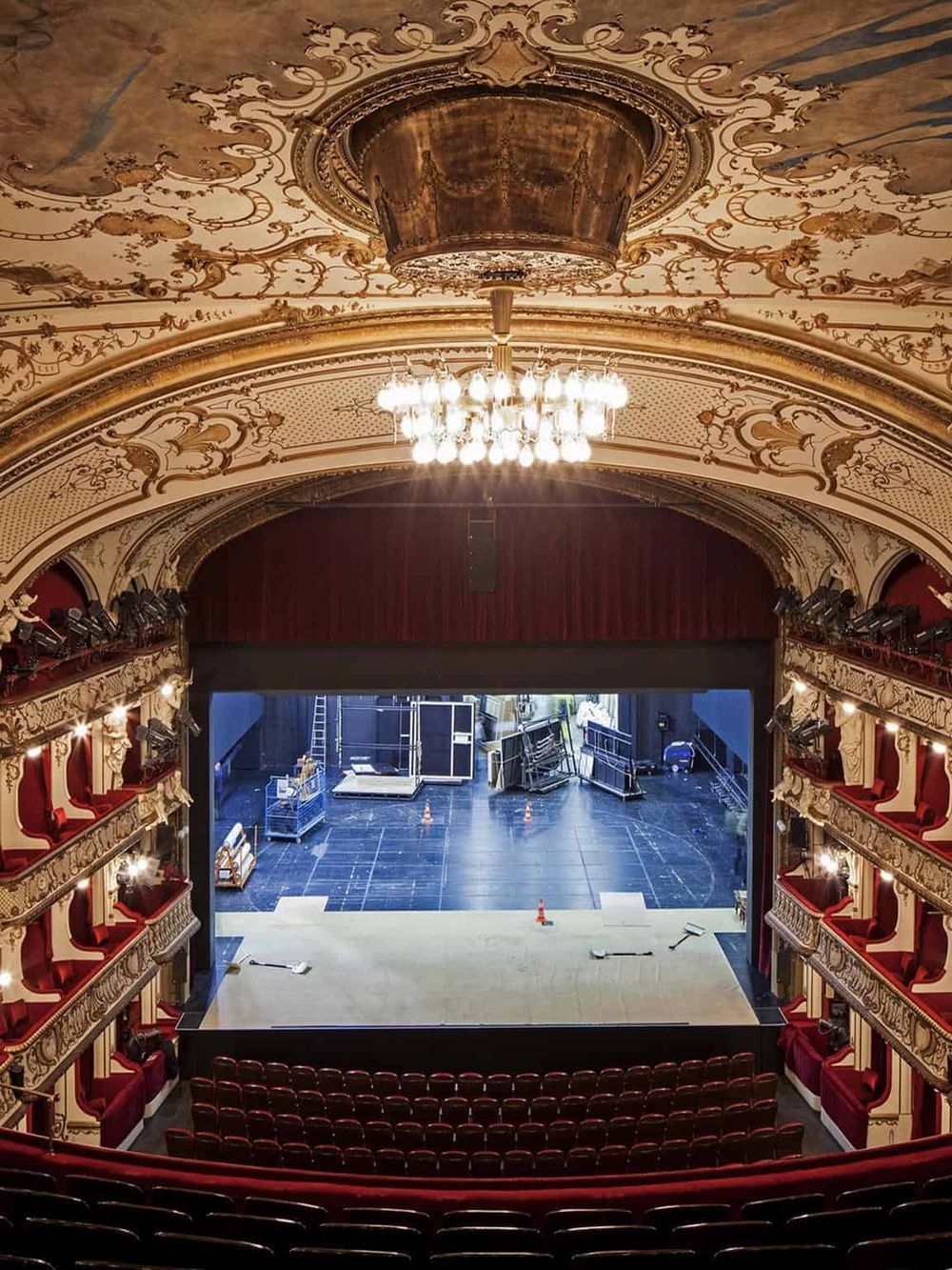 Elegant historic theater interior with ornate ceiling, chandelier, and stage under renovation, ideal for event planning.
