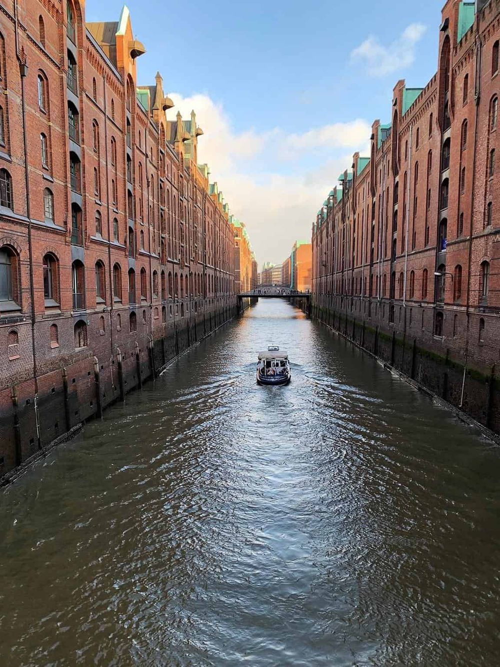 Historic brick warehouse buildings along a canal with a boat in Hamburg, Germany.