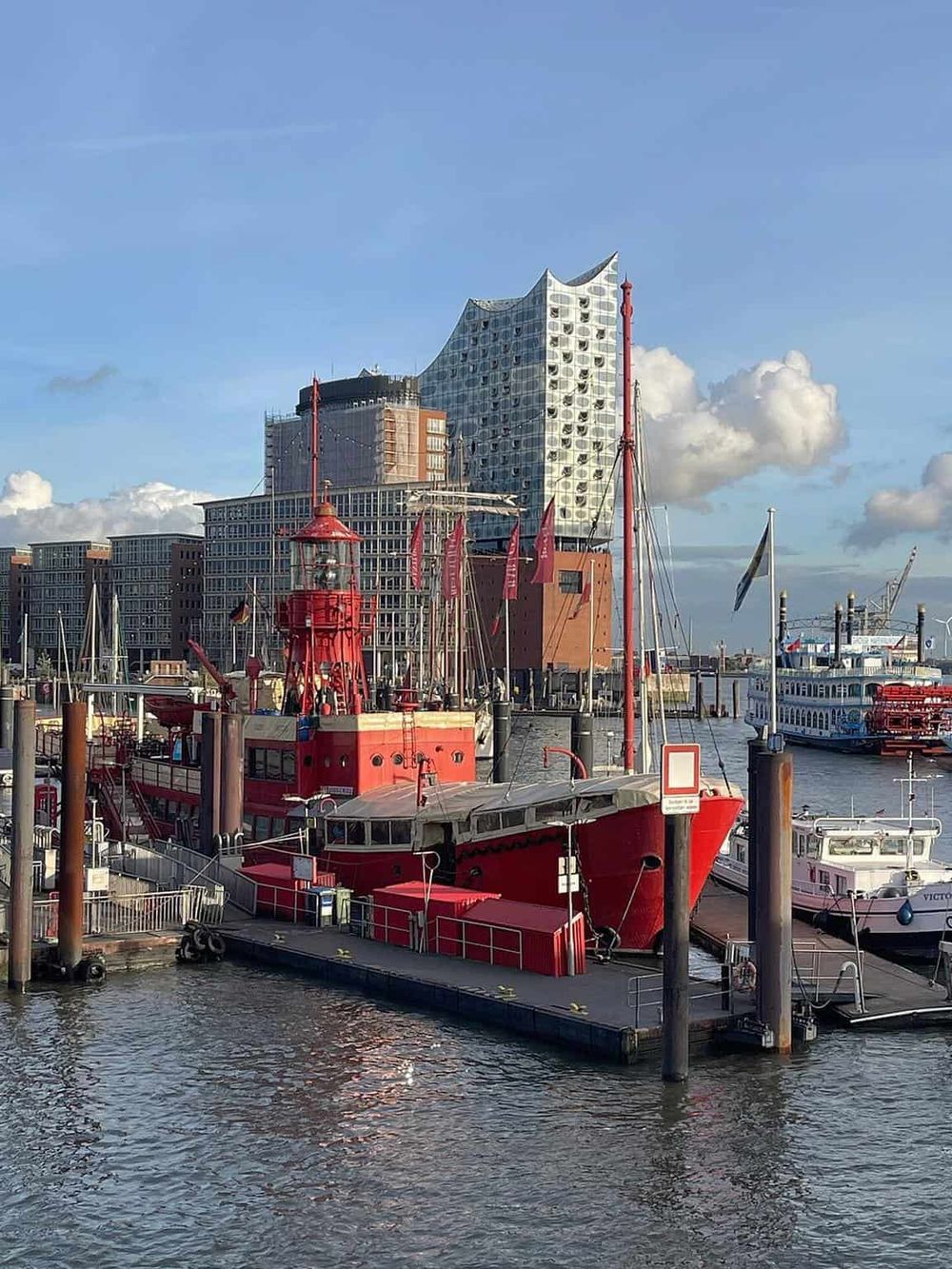 Colorful harbor with ships and modern architecture in the background, showcasing navigation and travel services.