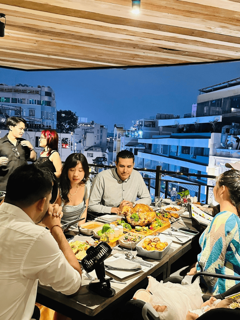 Vibrant rooftop dinner scene with diverse group enjoying food and city views at QuestForDirections.