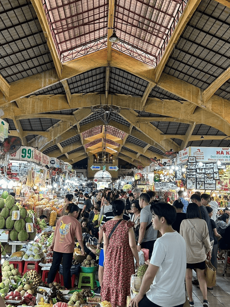 Vibrant market scene at QuestForDirections, showcasing busy stalls, fresh fruits, and bustling shoppers in an indoor marketplace.