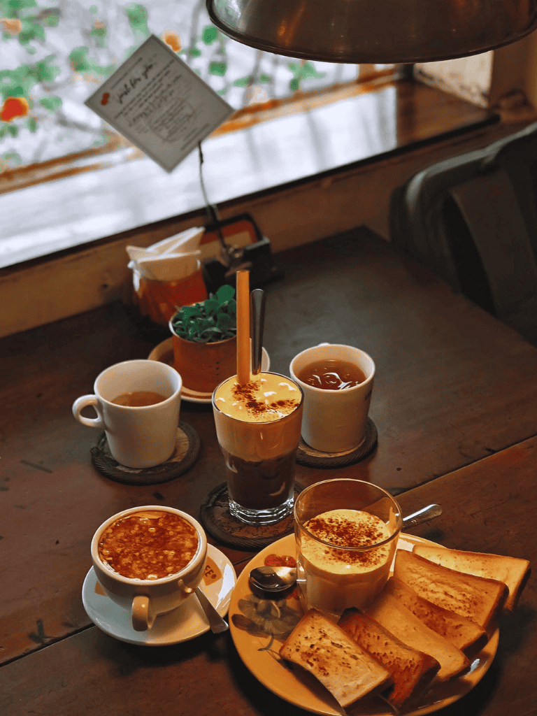 Warm coffee and dessert drinks on a cozy wooden table with toast, ideal for cafe ambiance.