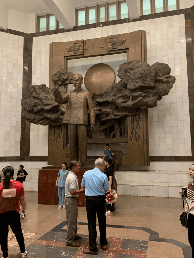 Bronze statue of Mao Zedong at Quest for Directions museum in China. Visitors observe the iconic leader's sculpture in a grand hall.