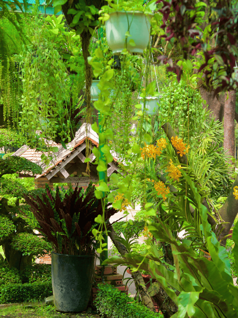 Lush green garden with hanging pots, vibrant plants, and garden ornaments for outdoor relaxation and plant enthusiasts.