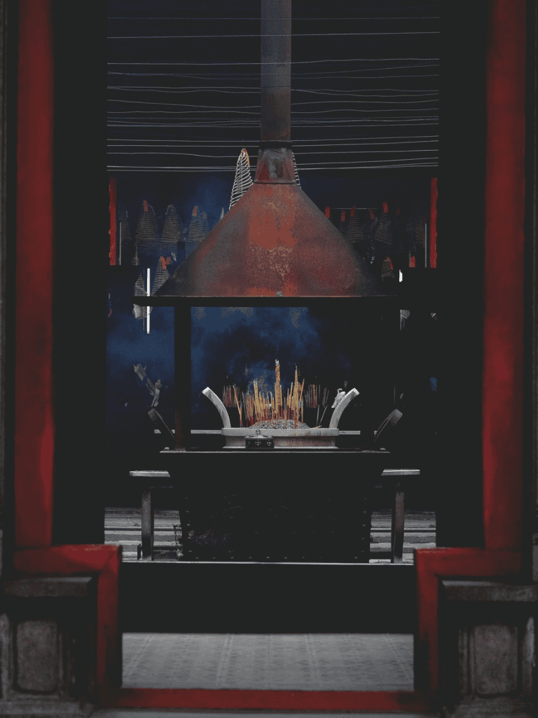 Smoldering incense burner with smoke rising, traditional Asian temple setting, spiritual ambiance, cultural ritual, QuestForDirections.