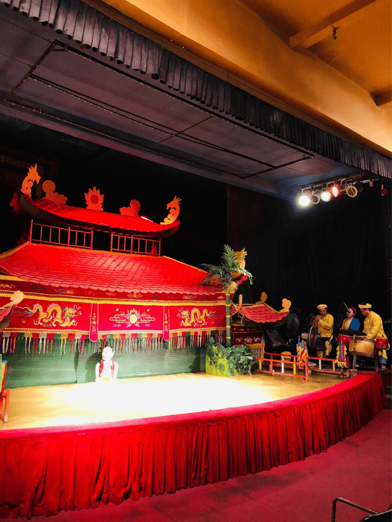 Colorful traditional Vietnamese puppet theater stage with performers, vibrant decorations, and cultural symbols.