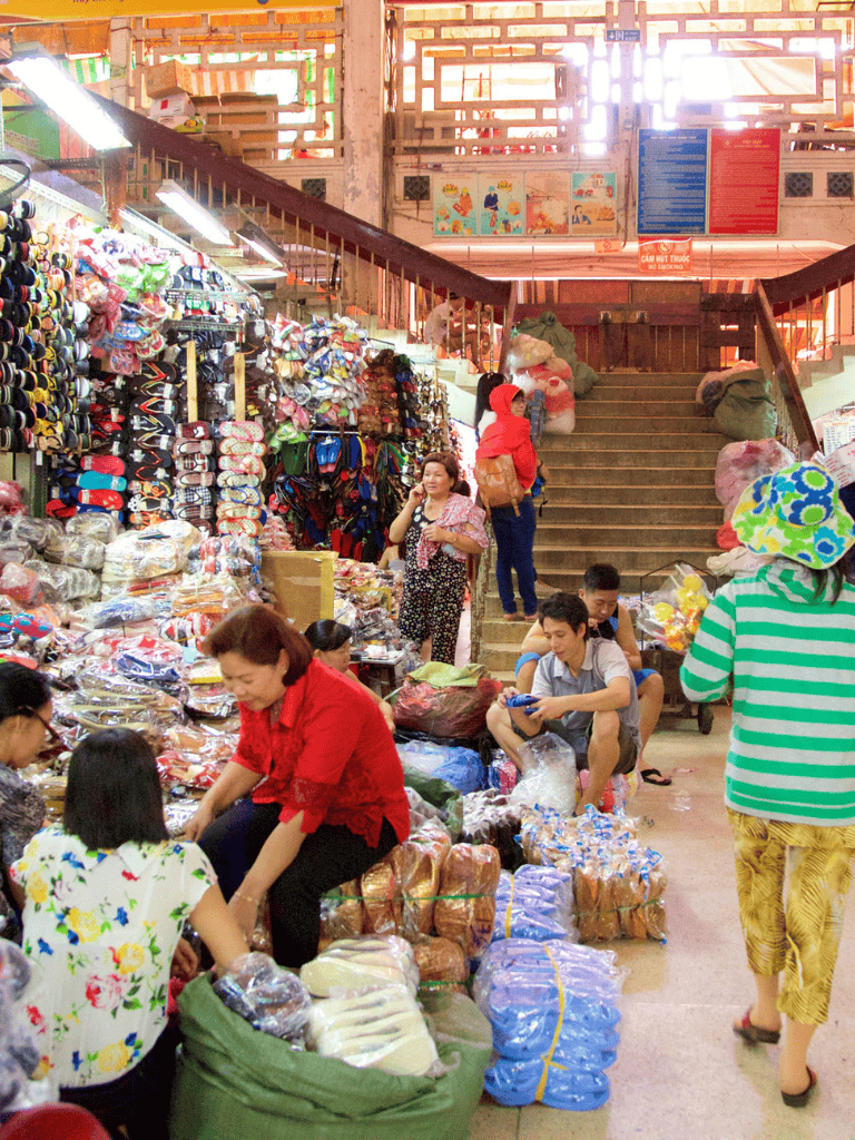 Clothing and shoe market stall in an indoor shopping area, vibrant and busy scene.